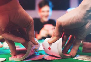 Dealer shuffling poker deck in front of man