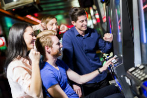 Young group of people gambling in a casino playing slot and various machines